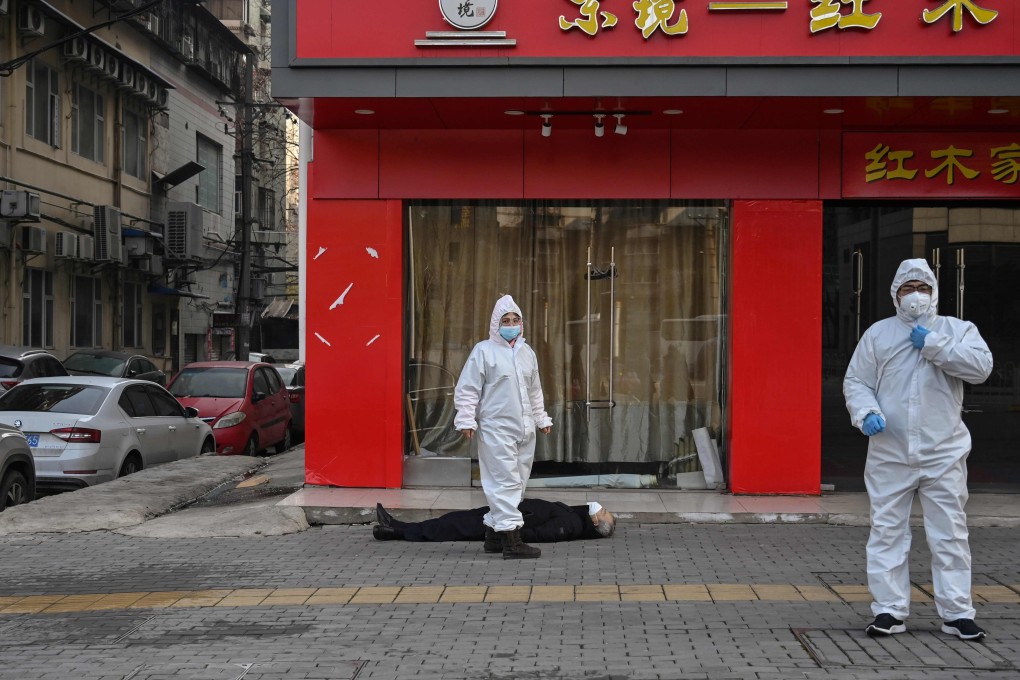 Officials in protective gear check on an elderly man in a mask who collapsed and died on a street near a hospital in Wuhan on January 30. Photo: AFP