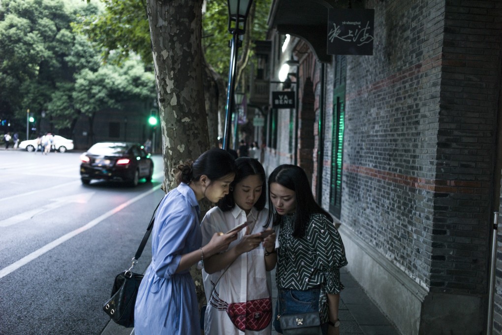 Women look at their smartphones in Xintiandi district, a shopping area, in Shanghai. Photo: AFP