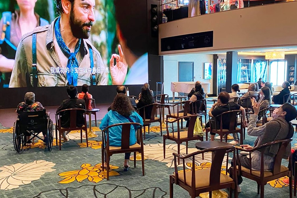 Passengers stranded on the World Dream watch a film to kill time. Photo: Handout