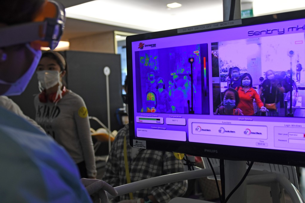 A staff member checks the body temperatures of charter flight passengers at Changi Airport on February 5, 2020. Photo: Xinhua