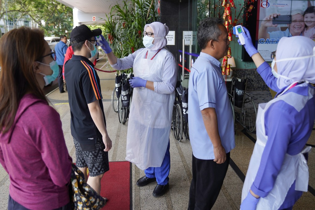 Nurses check the temperatures of visitors as part of the coronavirus screening procedure at a hospital in Kuala Lumpur. Photo: AP