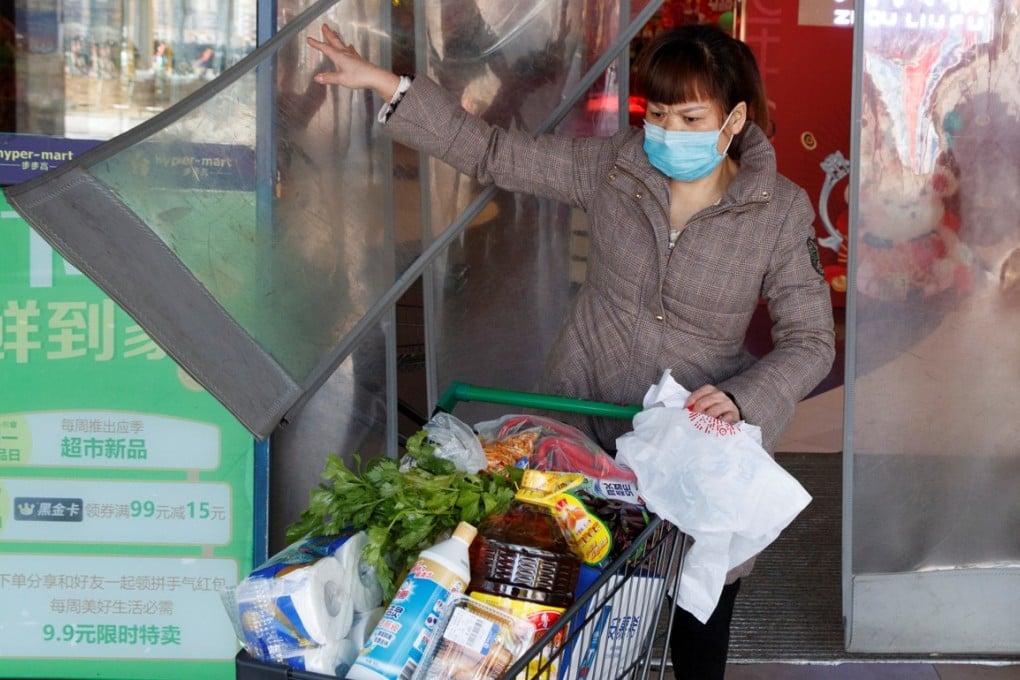 A woman wearing a face mask leaves a supermarket with a loaded shopping trolley in Changsha in China’s Hunan province on January 29. China’s market regulator has vowed to punish businesses engaging in price-gouging. Photo: Reuters