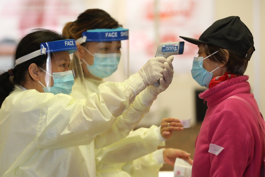 Medical workers take the temperature of a woman at Queen Elizabeth Hospital, following the coronavirus outbreak. Photo: Winson Wong