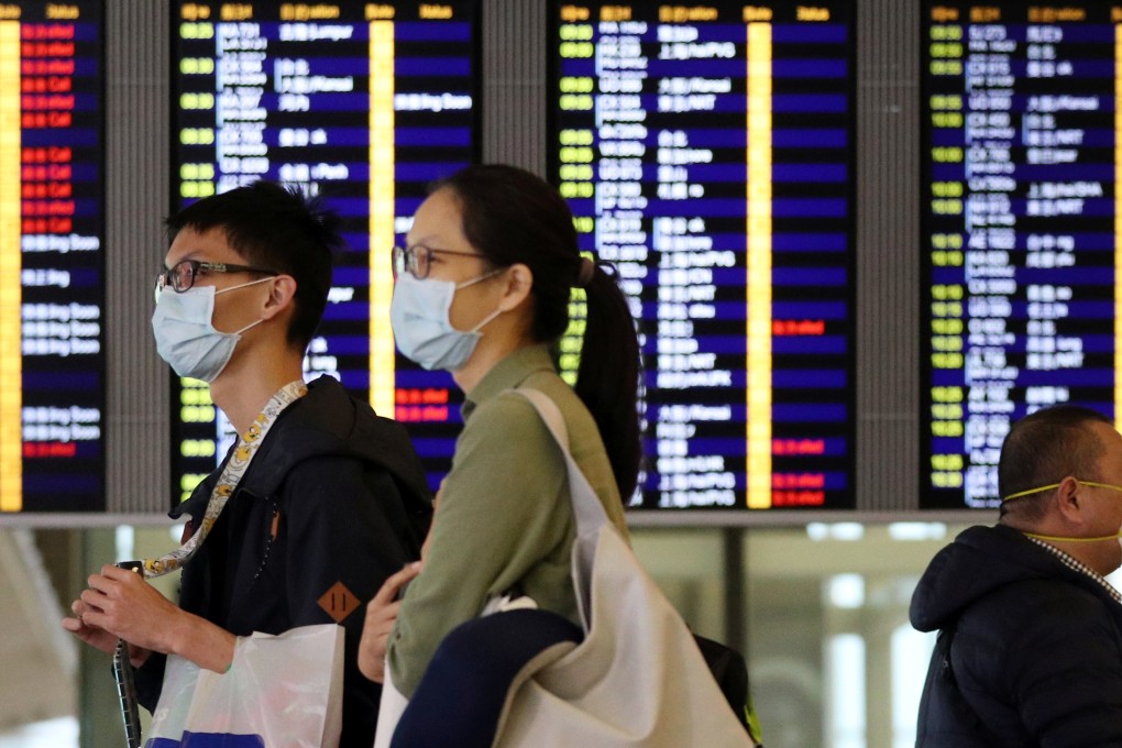Passengers wear protective masks as they walk past an information board at Hong Kong International Airport on February 7. Photo: Reuters
