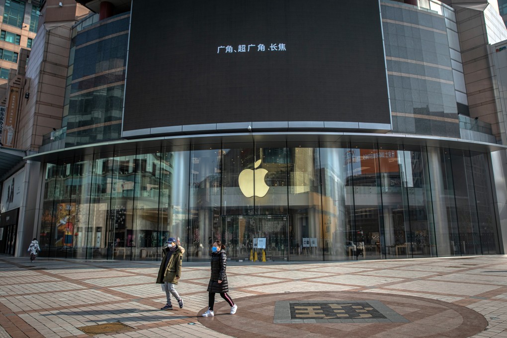 People wearing protective face masks walk past a closed Apple Store at the Wangfujing shopping district in Beijing on February 9. Photo: EPA-EFE