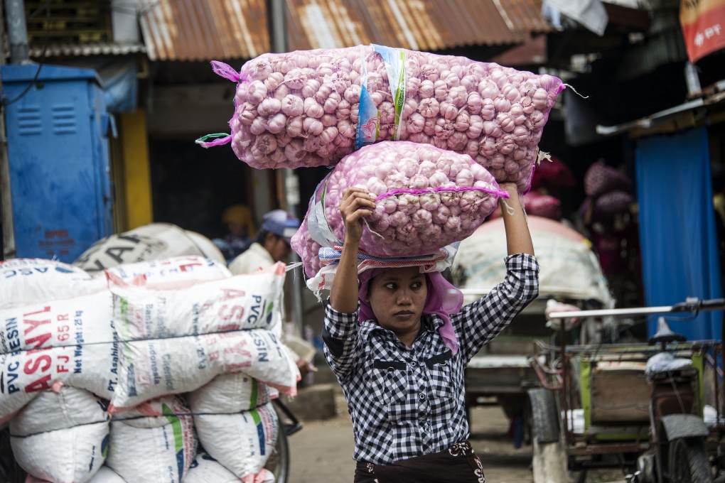An Indonesian woman carries bags of garlic at a market in Surabaya. Photo: AFP