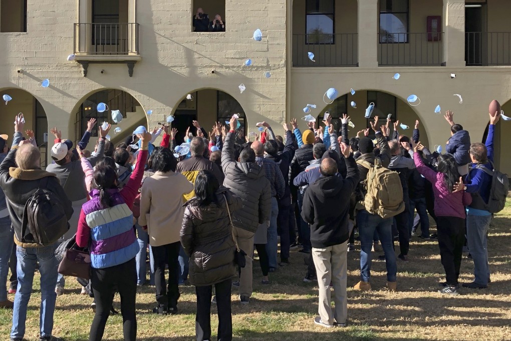 Evacuees throwing their masks in the air as they prepare to leave March Air Reserve Base in Riverside, California, on Tuesday. Photo: Riverside University Health System – Public Health via AP