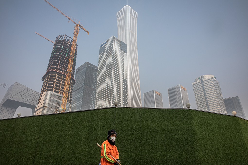 A municipal worker wearing a protective face mask walks next to a construction site in Beijing. The epidemic has brought economic activity in many sector, including real estate, to a standstill for the past two weeks. Photo: EPA-EFE