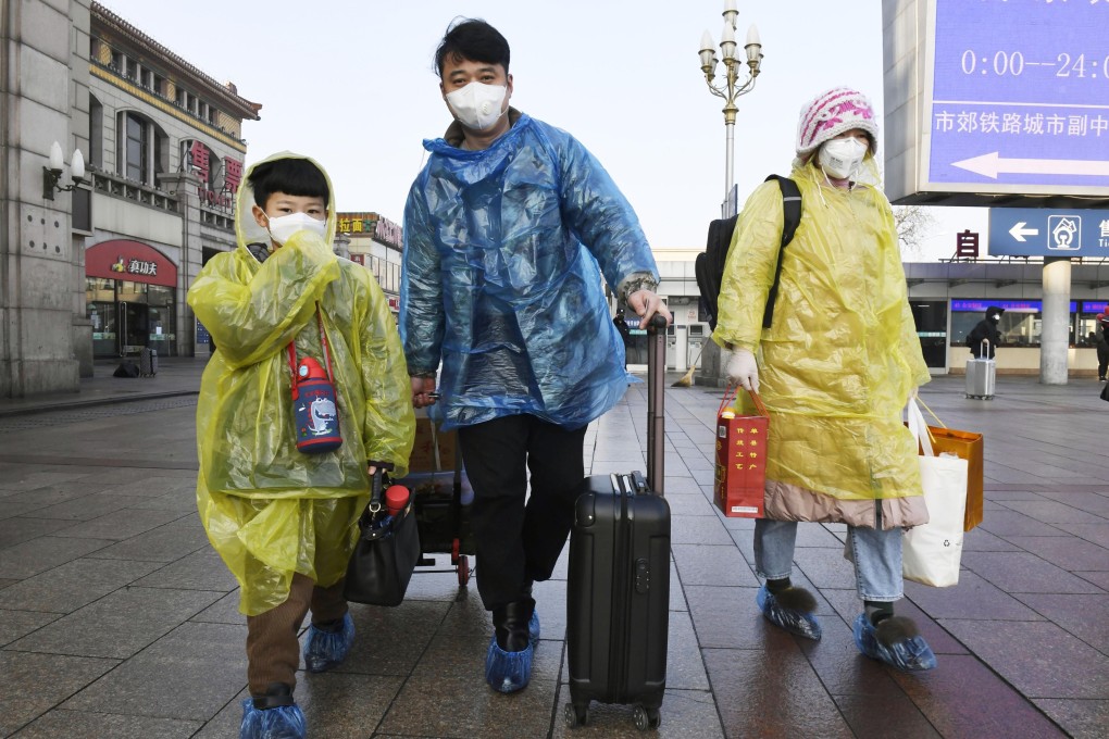 Passengers wear masks and raincoats at Beijing Station on Monday to protect themselves from the coronavirus. Photo: Kyodo