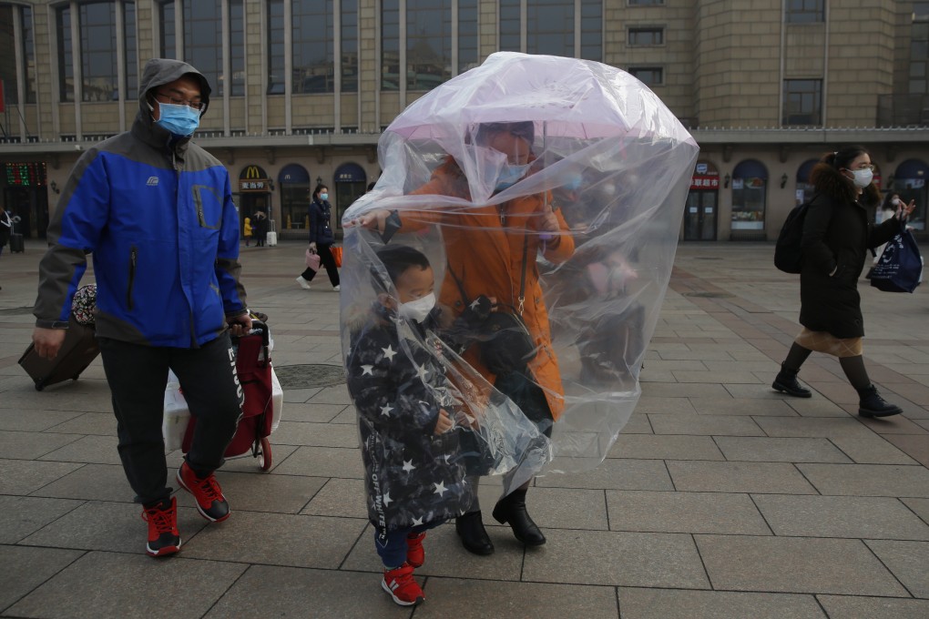 Masks, umbrellas – and even plastic bags. People take precaution against the coronavirus outbreak at the Beijing railway station on Tuesday. Photo: EPA-EFE