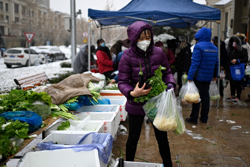 A woman wearing a mask buys vegetables at an open market in Beijing on February 2, after an outbreak of virus similar to the SARS pathogen. Photo: AFP