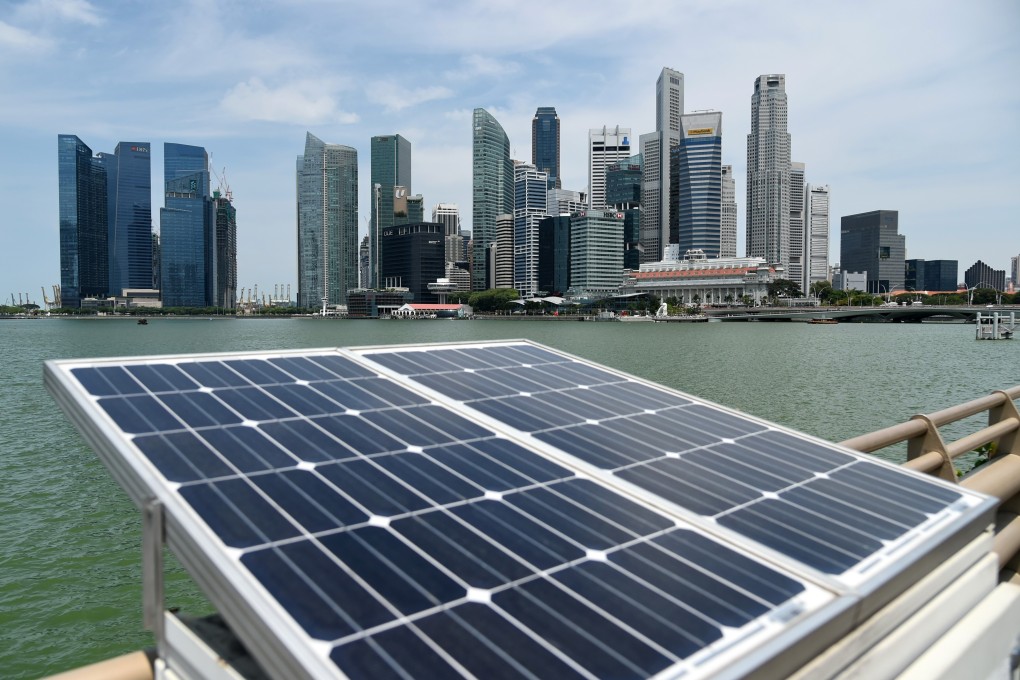 Solar panels used to power walkway lights are positioned along the Marina bay overlooking the skyscrapers of Singapore on April 26, 2016. / AFP PHOTO / ROSLAN RAHMAN
