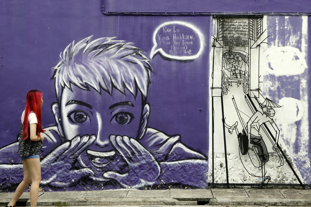 A woman looks at street art on a wall in George Town on the island of Penang, Malaysia, in November 2017. Photo: AP