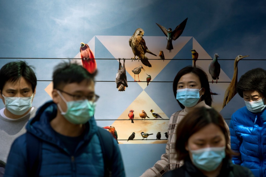 Pedestrians wearing protective masks near a hoarding displaying HSBC logo in Hong Kong on January 31 as the coronavirus outbreak grips the city. Photo: Bloomberg