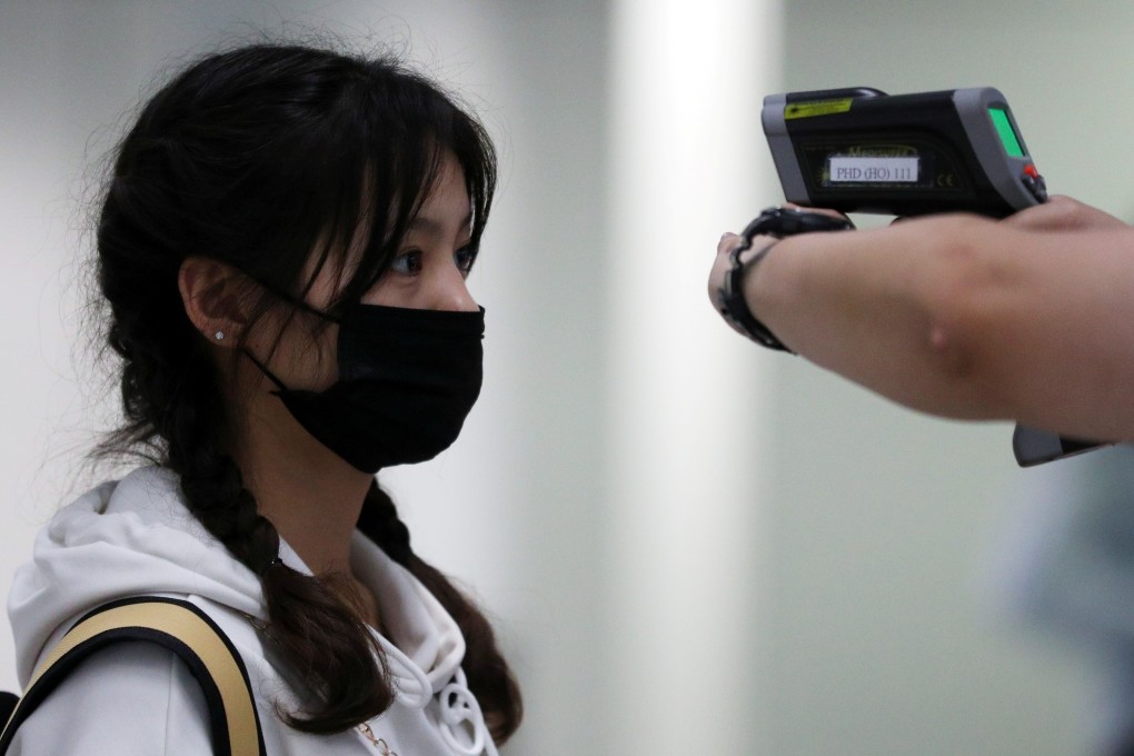 A passenger arriving into Hong Kong International Airport gets her temperature checked by a worker using an infrared thermometer. Photo: Reuters