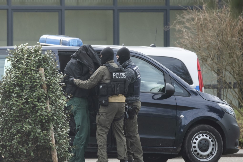 An unidentified person is brought to the Federal Supreme Court by police officers in Karlsruhe, Germany. Photo: dpa via AP