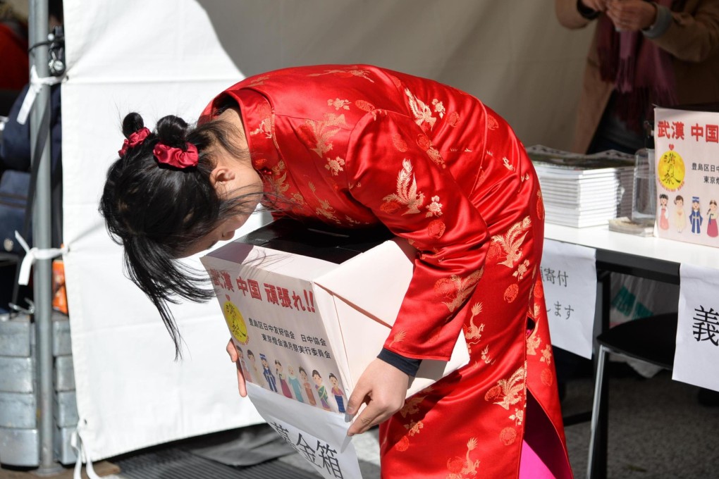 A Japanese girl in Tokyo wearing a red Chinese cheongsam bows deeply to passers-by with a donation box in hands to raise money to help Chinese affected by the coronavirus. Photo: Xinhua