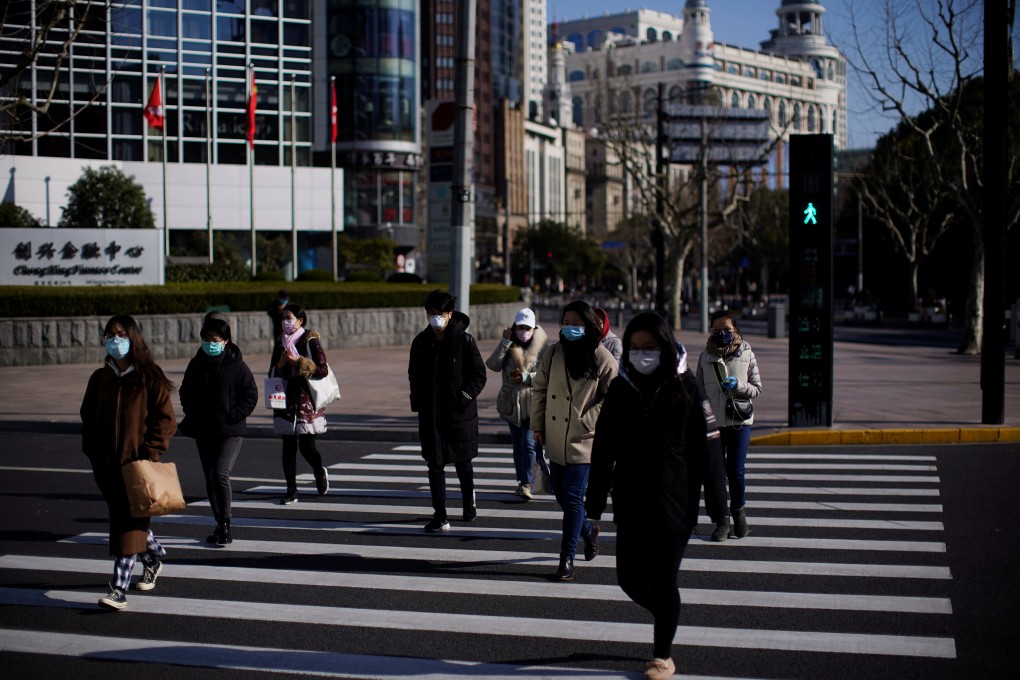 Pedestrians wearing face masks cross a road in Shanghai. The city has seen a high recovery rate among patients infected by the coronavirus. Photo: Reuters
