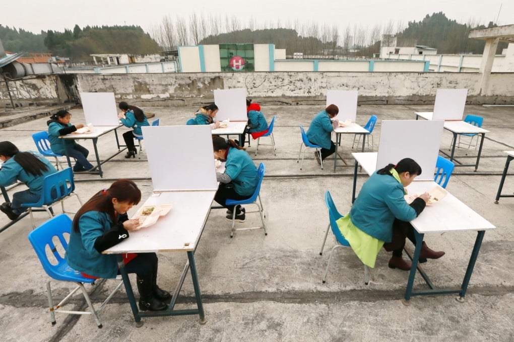 Workers have lunch on the roof of the building of an electronics factory in Suining city in China's Sichuan province to prevent the spread of the coronavirus. Photo: EPA