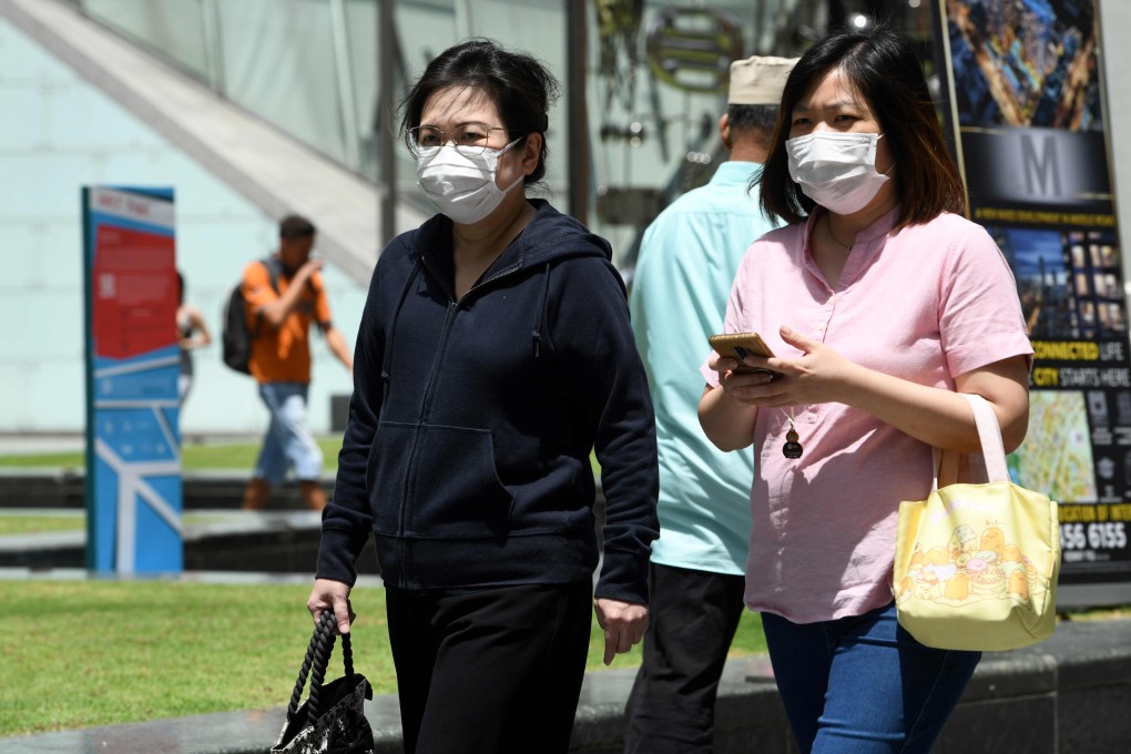 Two women wearing protective face masks, amid concerns over the spread of the COVID-19 coronavirus, walk on the street in Singapore on February 14, 2020. Photo: AFP