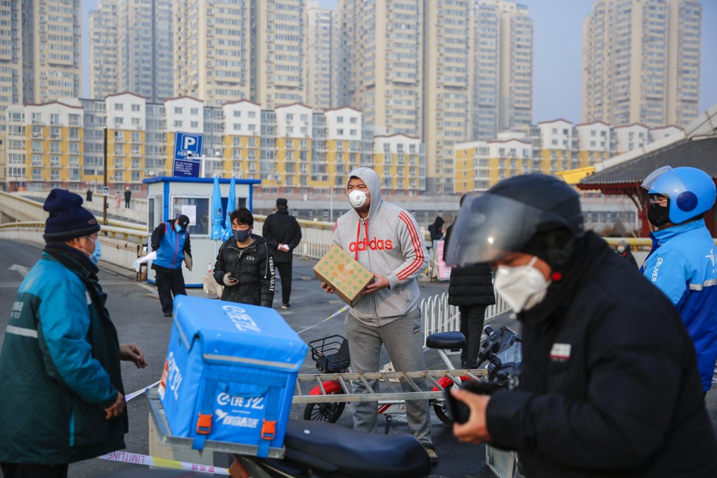 A man wearing protective mask gets a package from a delivery company courier outside a residential area in Beijing on February 12. Photo: EPA-EFE