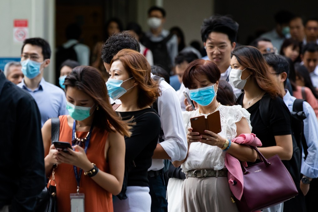 People stand in line for temperature checks outside an office building in the central business district of Singapore. Photo: Bloomberg