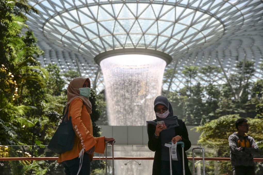 Tourists wearing protective masks stand near the Rain Vortex at the Jewel Changi Airport mall in Singapore. Photo: EPA-EFE