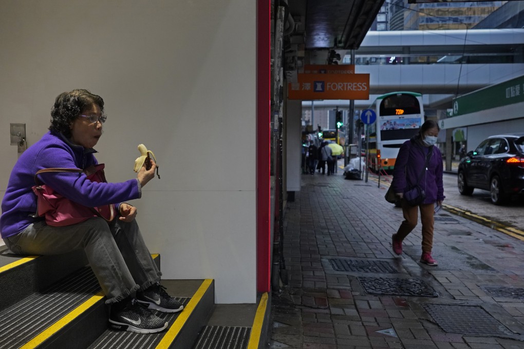 A woman takes off her face mask for a moment to eat a banana on a street in Hong Kong on February 14. Masks are effective only when used in combination with frequent hand-cleaning, and should not be touched while being used. The incorrect use of masks increases the risk of infection. Photo: AP