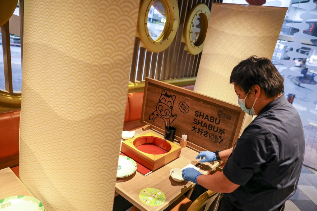 A worker at a Japanese restaurant sets up dividers between tables to ease coronavirus concerns for customers who still want to enjoy a hotpot. Photo: Winson Wong