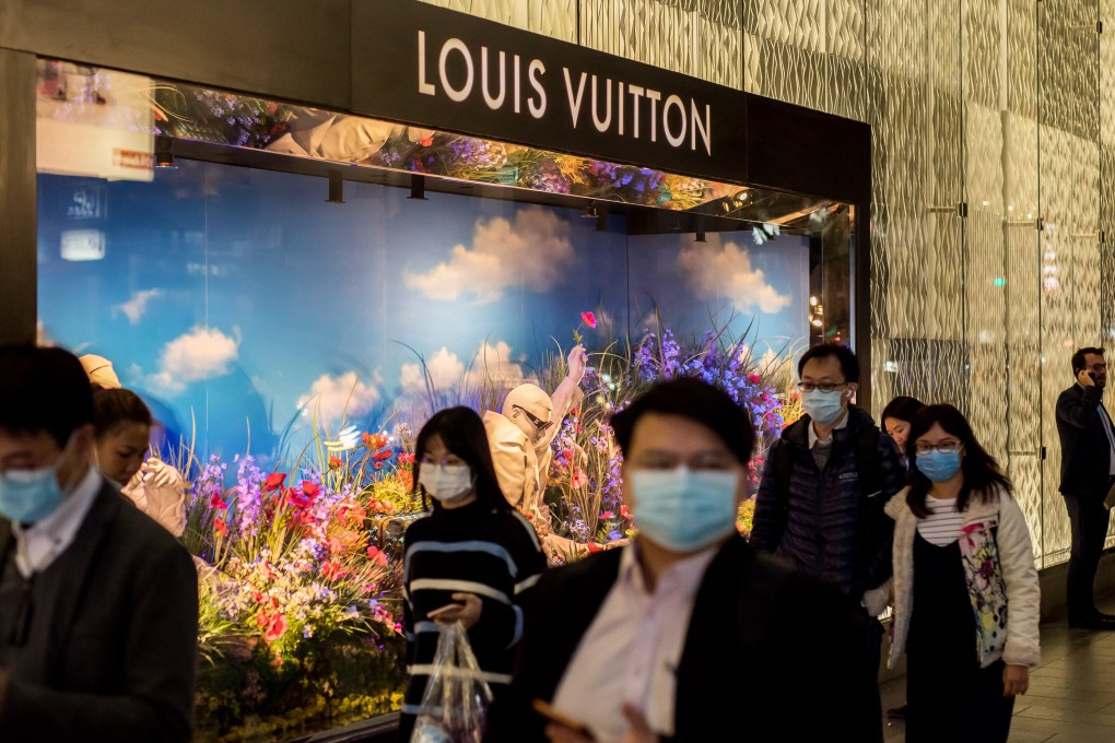 Pedestrians wearing protective masks walk past a Louis Vuitton shop in Central, Hong Kong. Several luxury brands have seen a drop in sales in China thanks to the spread of the coronavirus. Photo: Bloomberg