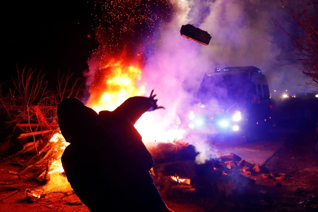 A demonstrator throws a stone towards a police van during a protest on Thursday in the village of Novi Sanzhary, Ukraine against the arrival of evacuees from China. Photo: Reuters