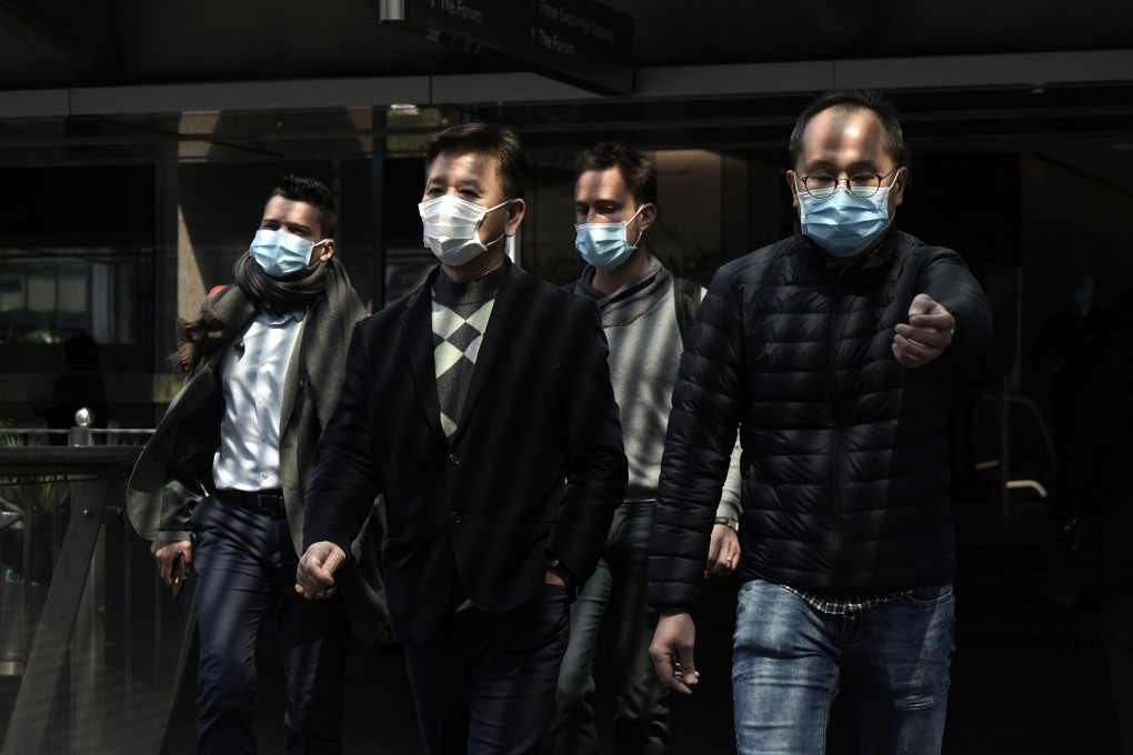 People wearing masks walk through the Hong Kong business district of Central on February 19. Given their wealth, resources and organisational heft, conglomerates in Hong Kong ought to be doing much more to contribute to bettering the coronavirus situation. Photo: AP