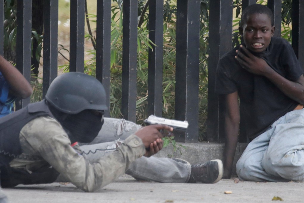 A boy gestures as a man in a Haitian National Police uniform aims a gun during the shoot-out. Photo: Reuters