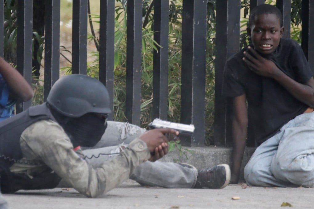 A boy gestures as a man in a Haitian National Police uniform aims a gun during the shoot-out. Photo: Reuters