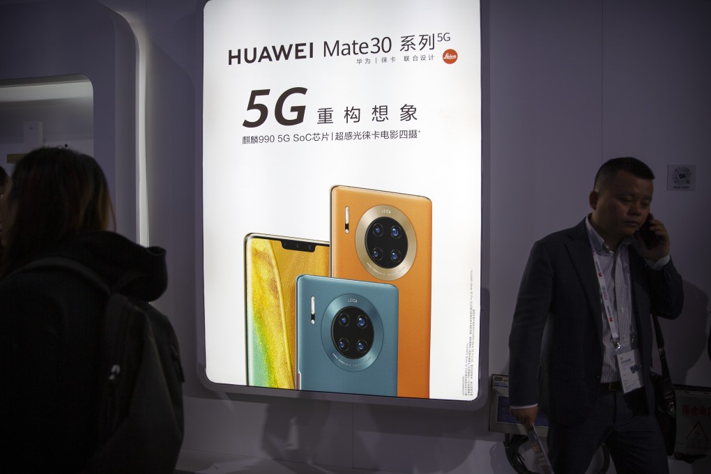 An attendee uses his smartphone near an advertisement for the Mate 30 smartphone from Huawei Technologies at the PT Expo in Beijing in October of last year. Photo: AP