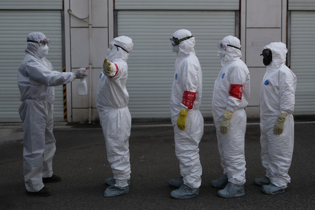 Volunteers in protective suits line up to be disinfected in Wuhan, provincial capital of Hubei province in central China. Photo: Reuters