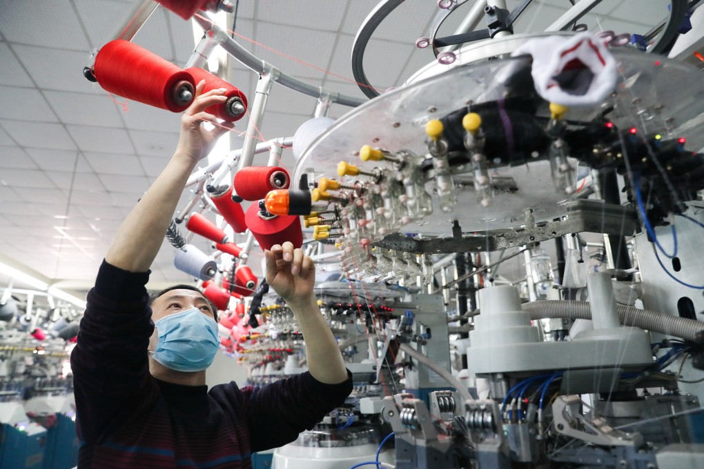 An employee wearing a face mask works on a production line manufacturing socks for export at a factory in Huzhou’s Deqing county, Zhejiang province, on February 19. Over the past month, the combination of an unprecedented quarantine on Hubei and draconian restrictions on intercity travel has brought the Chinese economy to a virtual standstill. Photo: China Daily via Reuters