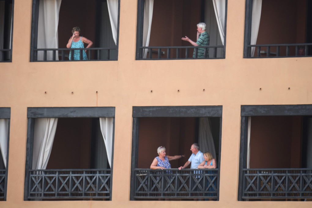 Tourists stand on the balcony of their rooms at the H10 Costa Adeje Palace Hotel in La Caleta, where hundreds of people were confined to their rooms. Photo: AFP