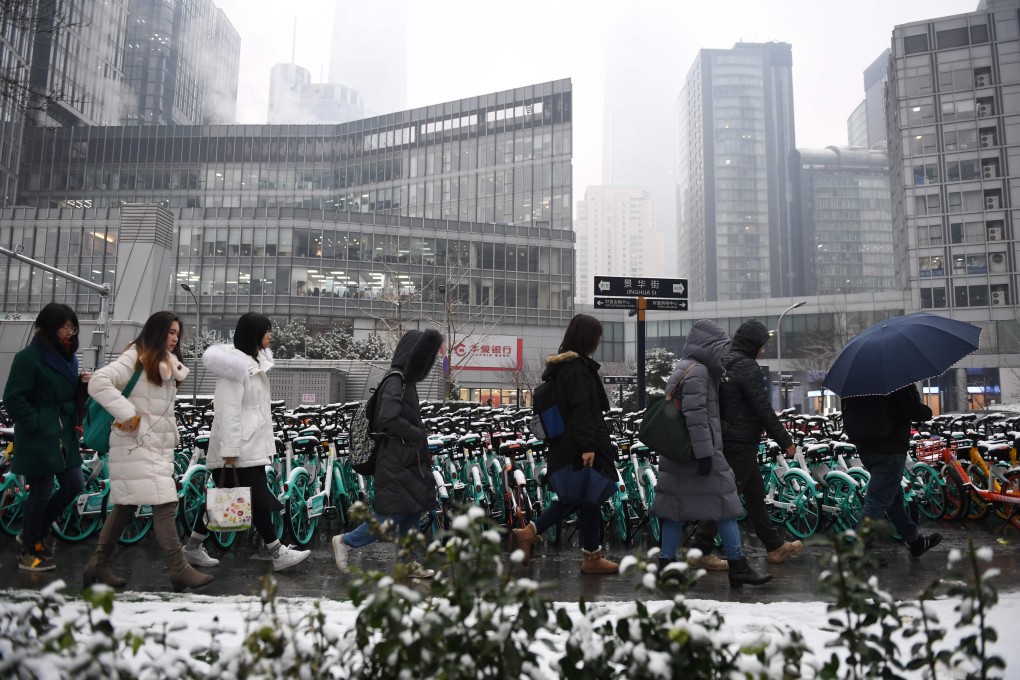 Office workers walk past buildings in Beijing's central business district, as they arrive for work on December 16, 2019. More than half have been telecommuting since the spread of the coronavirus over the Lunar New Year holiday. Photo: Agence France-Presse