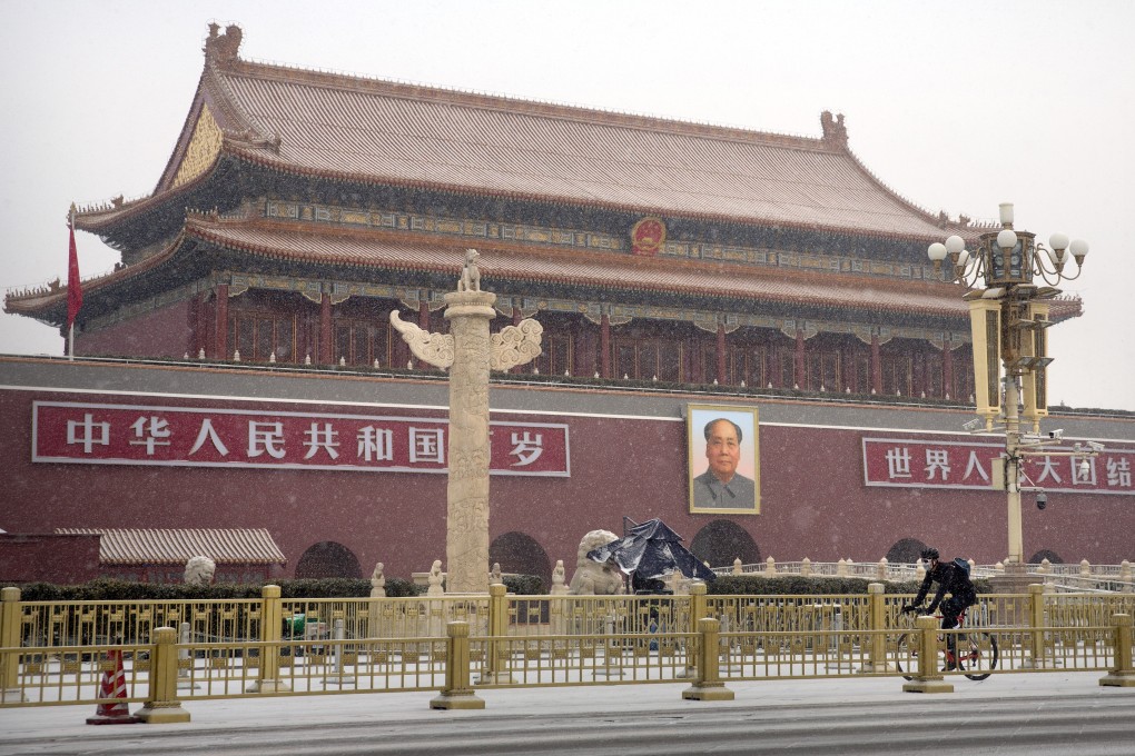 A man wears a face mask as he rides a bicycle past Tiananmen Gate in Beijing. Photo: AP