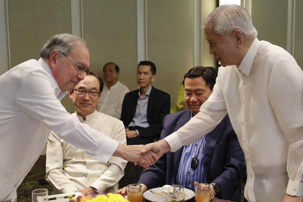 Former Philippines Foreign Secretary Albert del Rosario, right, shakes hands with Jose Manuel Romualdez, ambassador of the Philippines to the US. Photo: AP Photo
