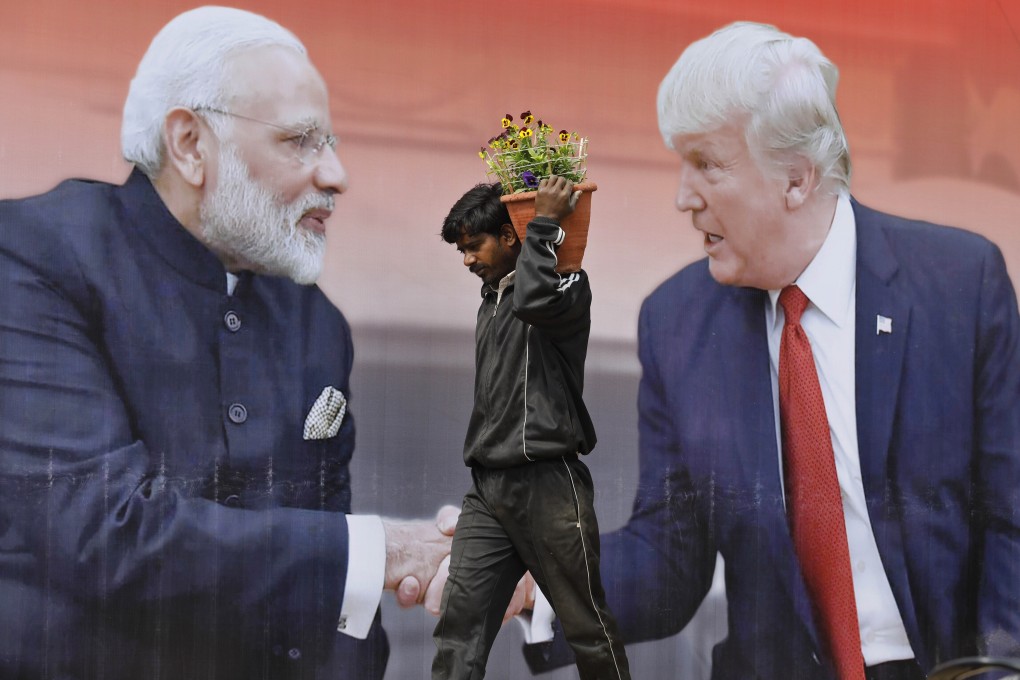 An Indian worker carries flowers to be planted past a hoarding featuring US President Donald Trump and Indian Prime Minister Narendra Modi in Agra, India, on February 23. Photo: AP