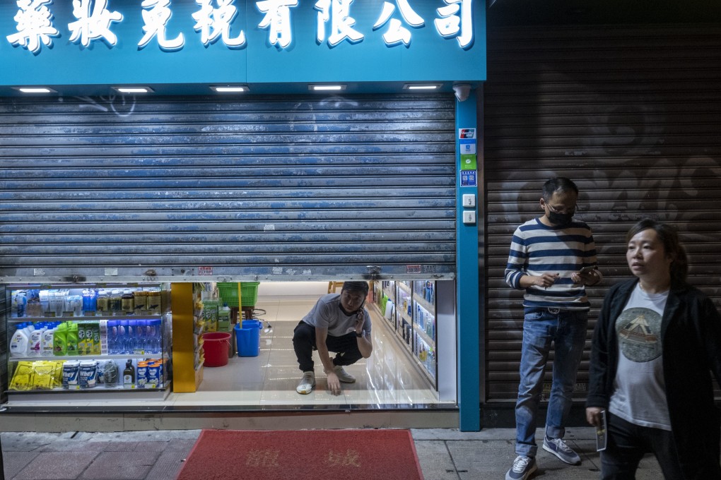 An employee looks out from a half-shuttered store in Tsim Sha Tsui, Hong Kong last December. Photo: Bloomberg