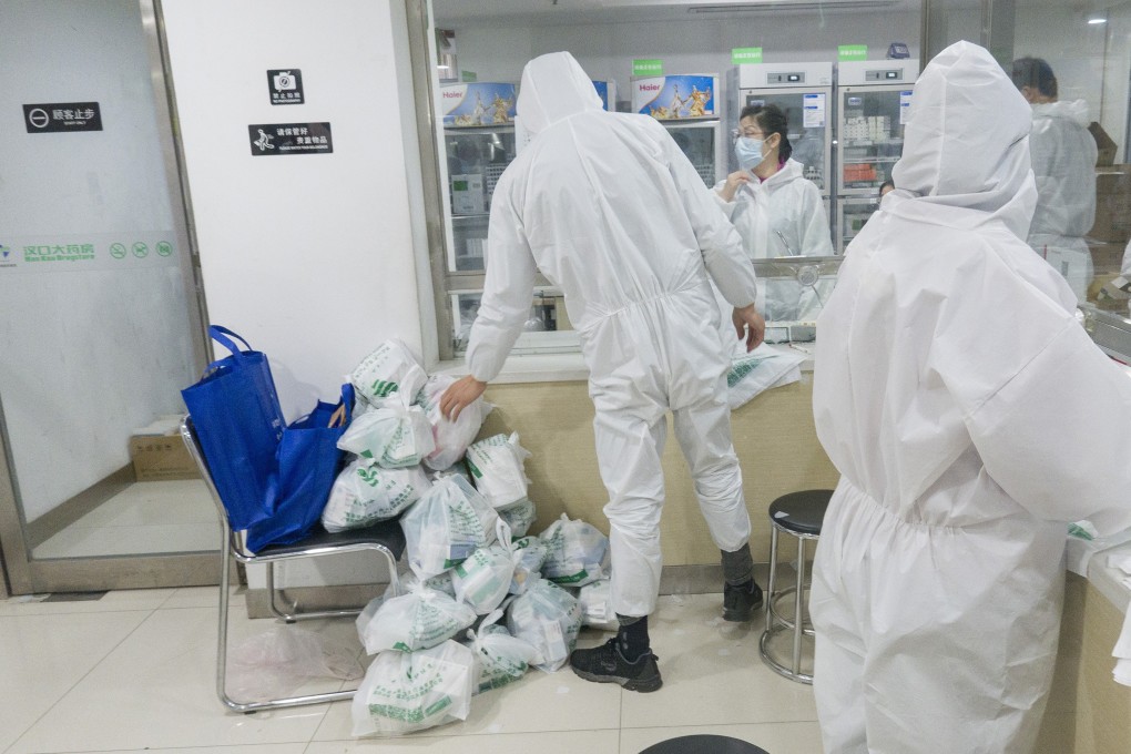 Community workers pick up medicine for sick residents from a pharmacy in Wuhan, Hubei province, on February 27. Photo: Xinhua
