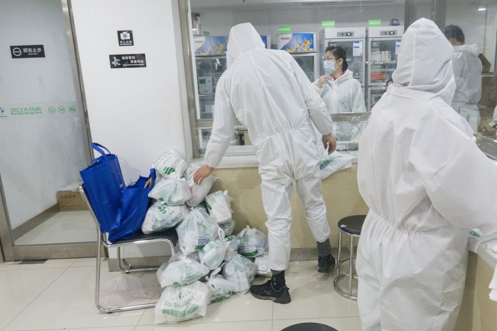 Community workers pick up medicine for sick residents from a pharmacy in Wuhan, Hubei province, on February 27. Photo: Xinhua