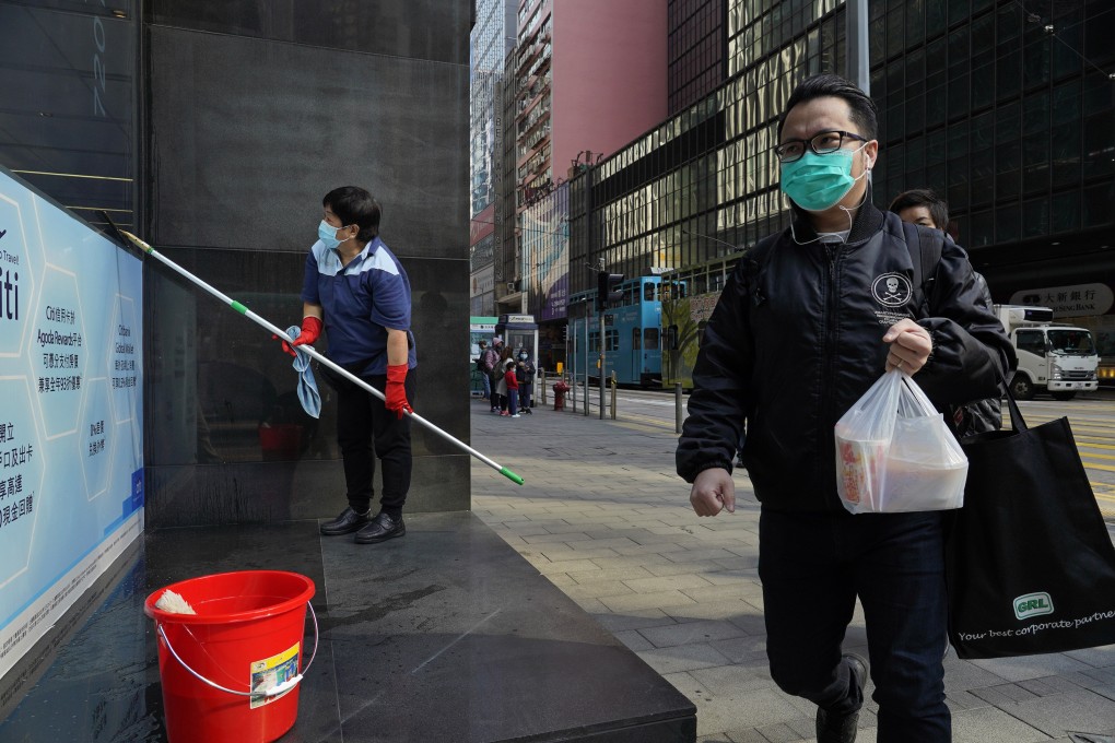 A man wearing face mask walks past a clean woman at a downtown street in Hong Kong on February 17. The Covid-19 disease is likely to spur wider application of technology in real estate market, according to JLL. Photo: AP