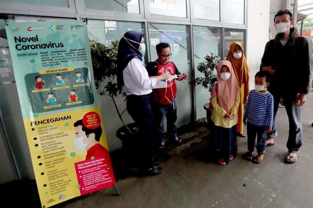 A commuter line medical officer provides masks to passengers at the Depok Baru Train Station in Depok, West Java, Indonesia. Photo: EPA-EFE