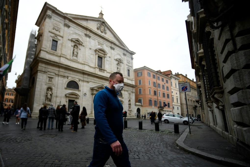 A man wearing a protective mask walks past the Church of St. Louis of the French in Rome. Photo: AFP