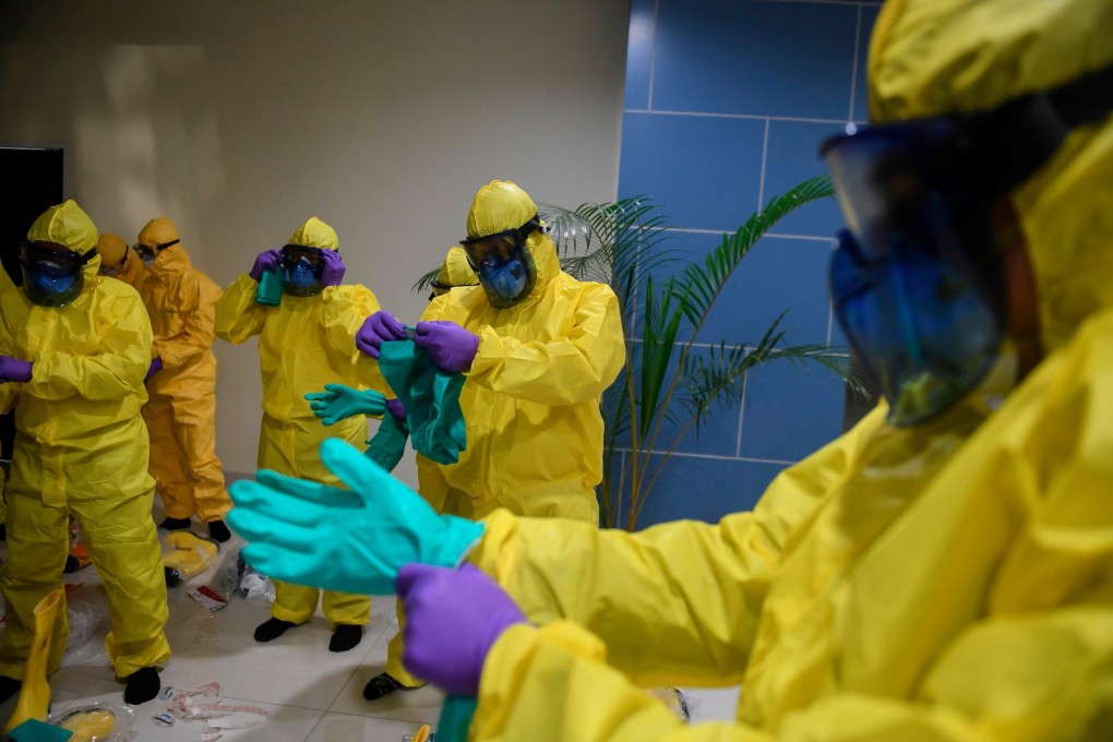 Indonesian officials put on protective suits before coming in to contact with possible coronavirus patients on Sunday. Photo: Reuters