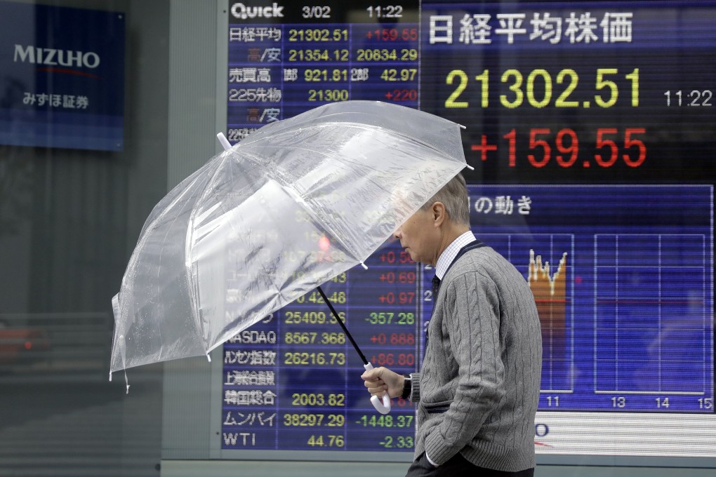 A pedestrian holding an umbrella walks past an electronic stock board outside a securities firm in Tokyo, Japan, on March 2. Photo: Bloomberg